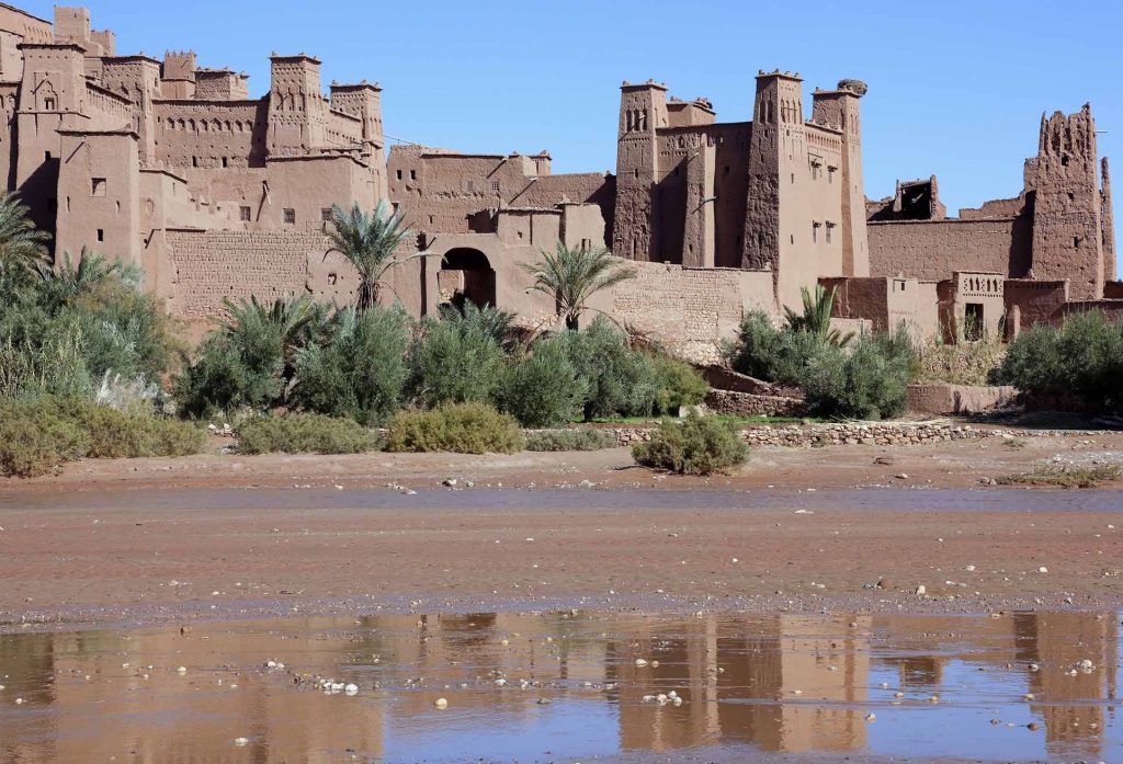UNESCO World heritage site Kasbah Ait Ben Haddou with water reflections and blue sky.